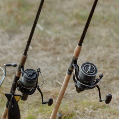 Detailed view of fishing rods with reels set up on grassy terrain, ideal for outdoor angling activities.
