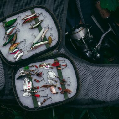 Top view of a well-organized fishing kit featuring colorful lures and a fishing reel.
